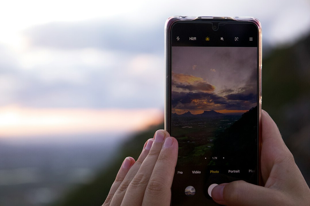 Smartphone showing a photo album of mountain landscapes on a table