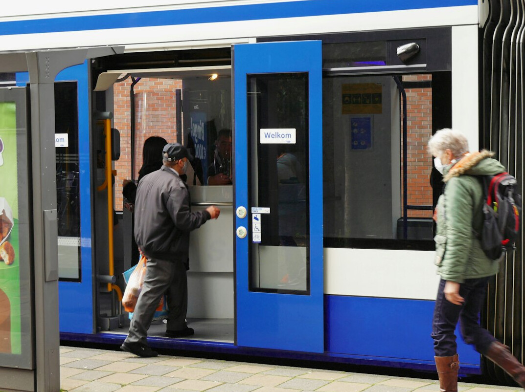 Senior man showing a digital ticket on a smartphone at a tram stop